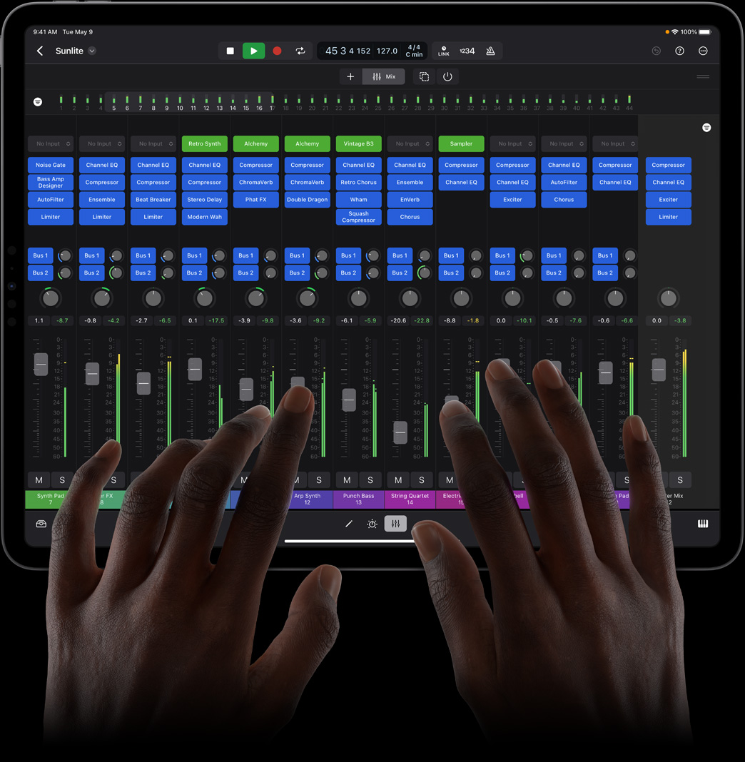 一双手点触 iPad Pro 屏幕，正在使用 iPad 版 Logic Pro 的全功能混音控制台。