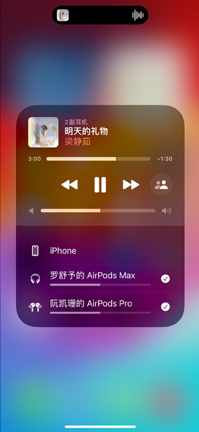 装有 AirPods Pro 的充电盒放在 iPhone 旁边。iPhone 与两副 AirPods 连接，可分别进行音量调节。