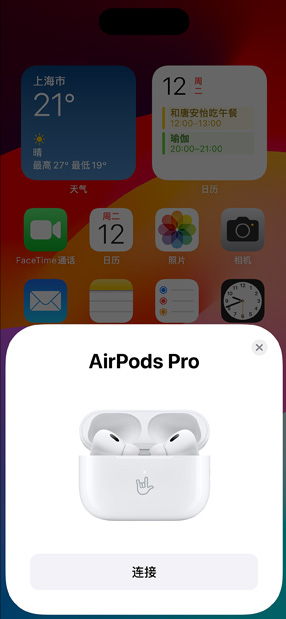 装有 AirPods Pro 的 MagSafe 充电盒放在 iPhone 旁边。iPhone 主屏幕上显示着弹出窗口，轻点连接按钮即可轻松配对 AirPods。