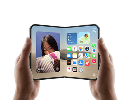 两只手拿着展开的 iPhone Duo，左侧界面显示一张女子照片，右侧界面显示主屏幕画面，其中包含信息、照片、相机和 App Store 等多种 app 图标。