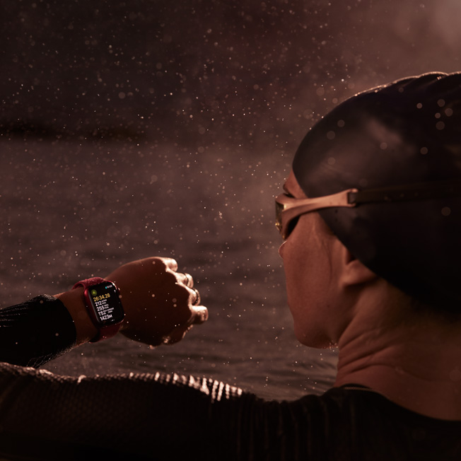 一位游泳者的图片，正注视着 Apple Watch。