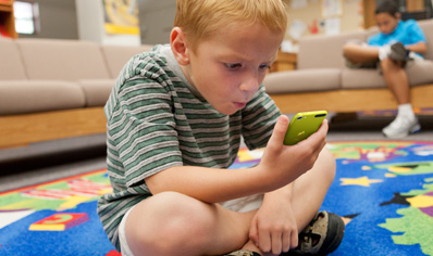 学生坐在地毯上聚精会神地看着 iPod touch