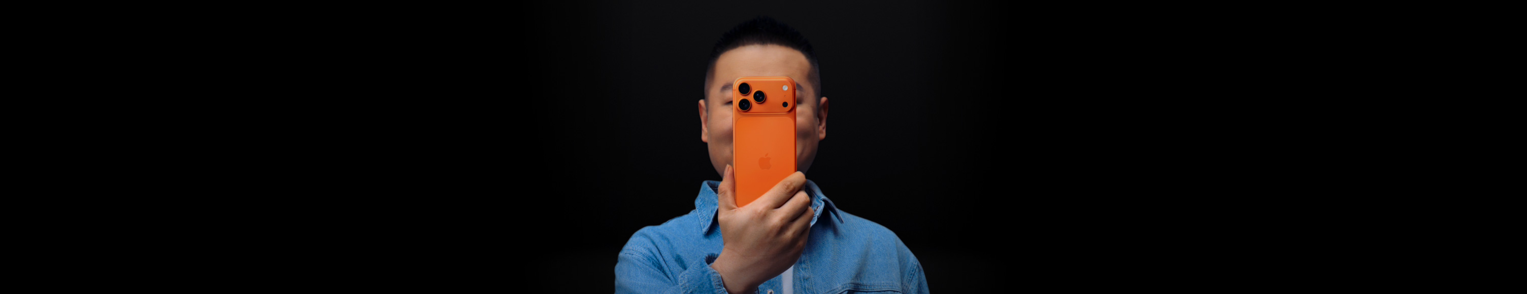 岳云鹏面对屏幕，拿着 iPhone 挡住自己的脸。