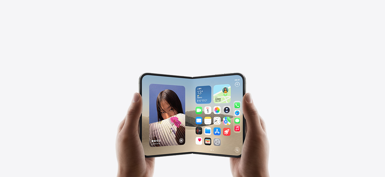 两只手拿着横向展开的 iPhone Duo，内屏显示主屏幕画面。