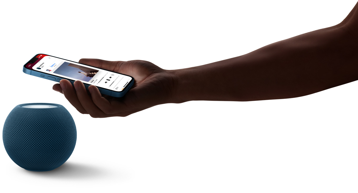 蓝色 HomePod mini 与 HomePod mini 上方一个人握持 iPhone 的手。iPhone 屏幕上的音乐 app 正在播放。