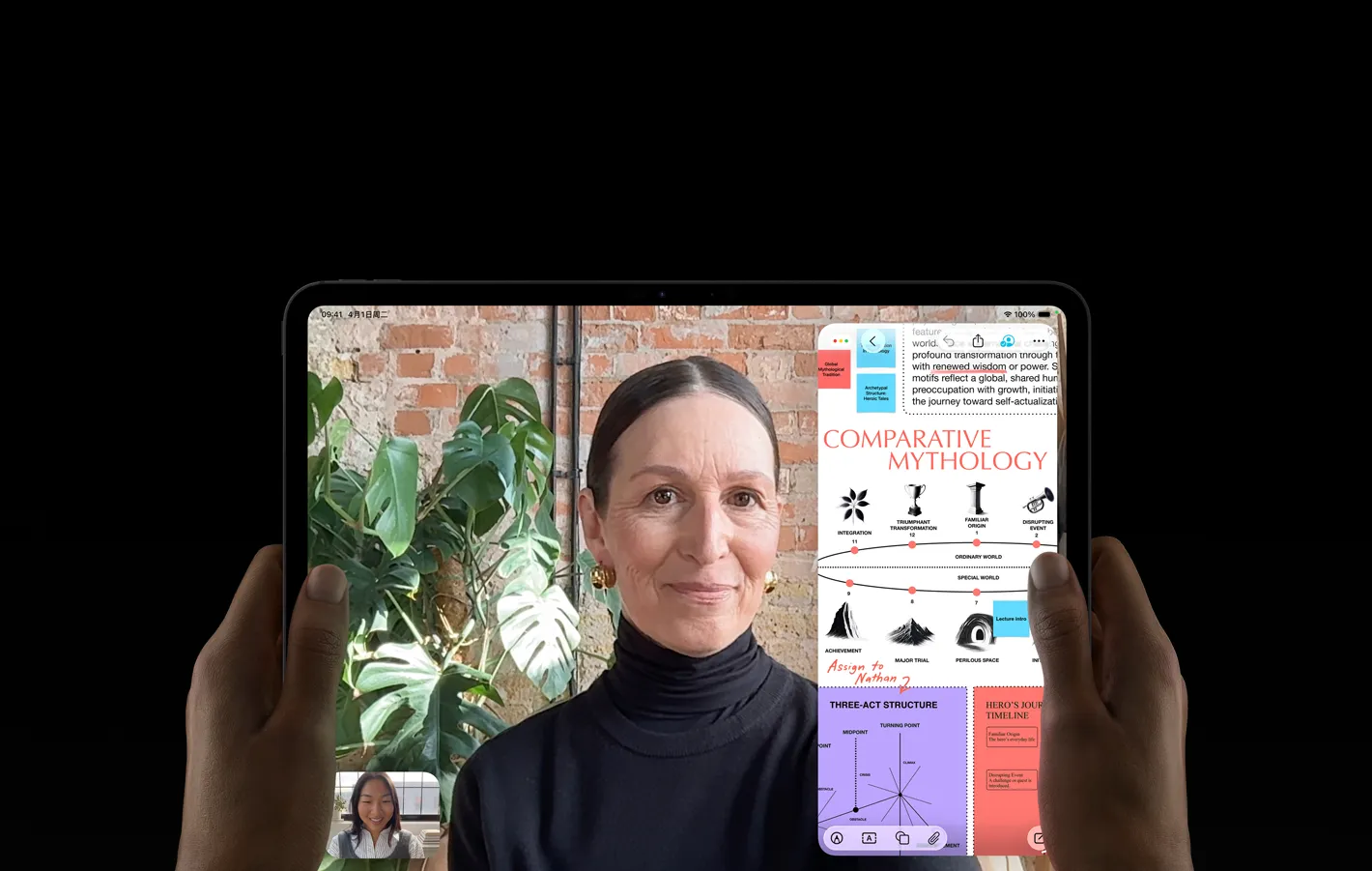 左右两只手拿着横屏放置的深空黑色 iPad Pro，正面展示圆角设计、黑色显示屏边框，屏幕显示 FaceTime 通话画面，以及一款教育类 app，呈现带有文字、图表和手写笔记的《比较神话学》演示文稿。