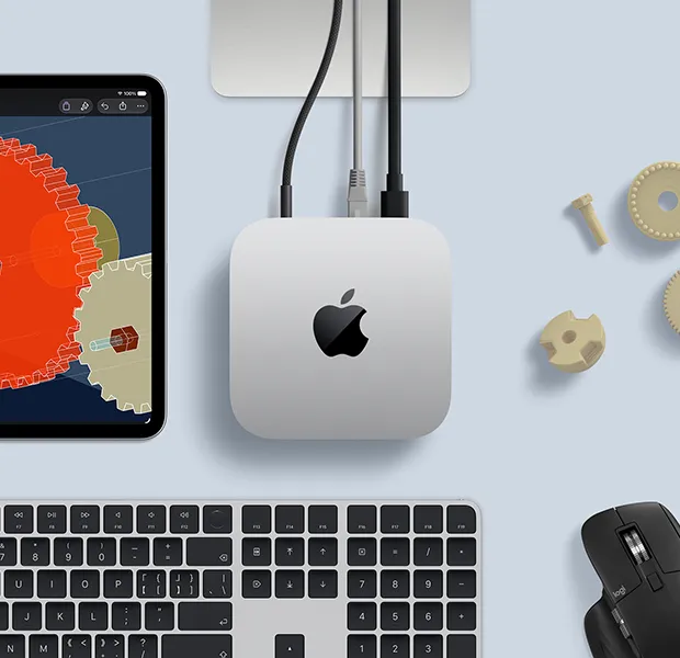 iPad 展示精细的 STEM 教具，Mac mini 位于画面中央，连接着电源线和 USB-C 线缆，Studio Display 支架部分显露出来，下方是带有触控 ID 的妙控键盘和 Logitech 鼠标。