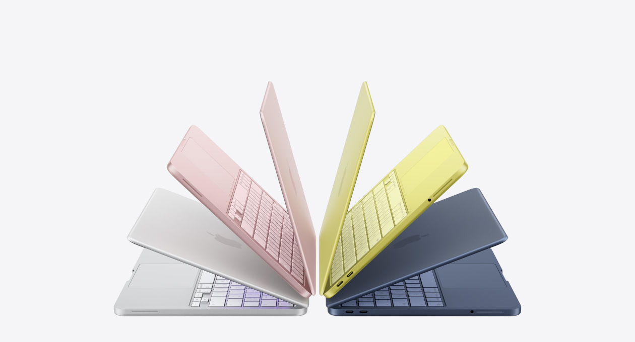 银色、桃粉色、柑橘黄色和靛蓝色 MacBook Neo 笔记本电脑呈略微打开状态，排列成一个拱形。