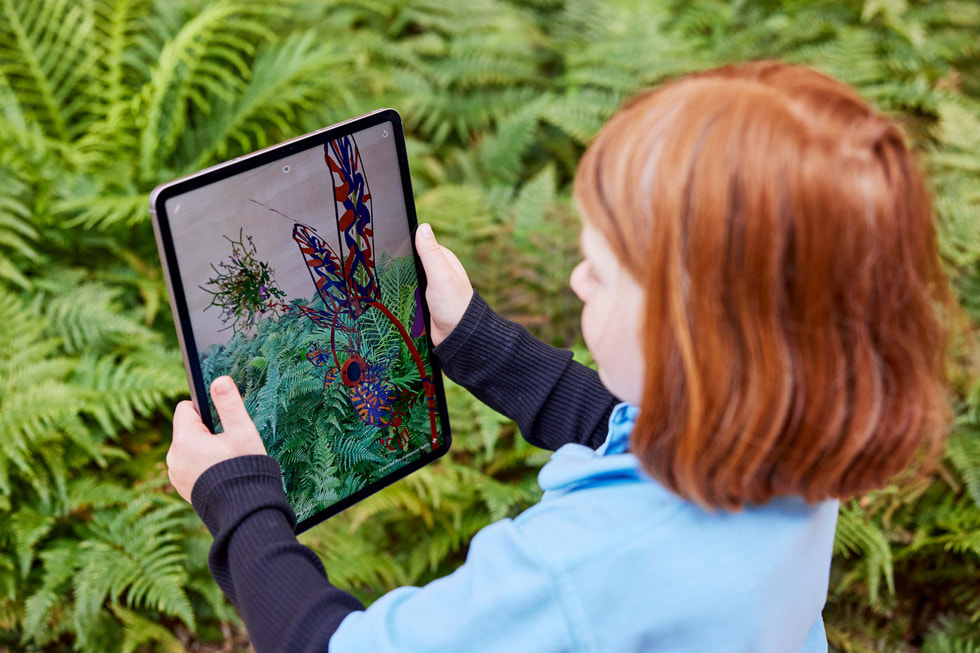 一名学生举起 iPad Pro ，在 Deep Field app 里探索户外植物。