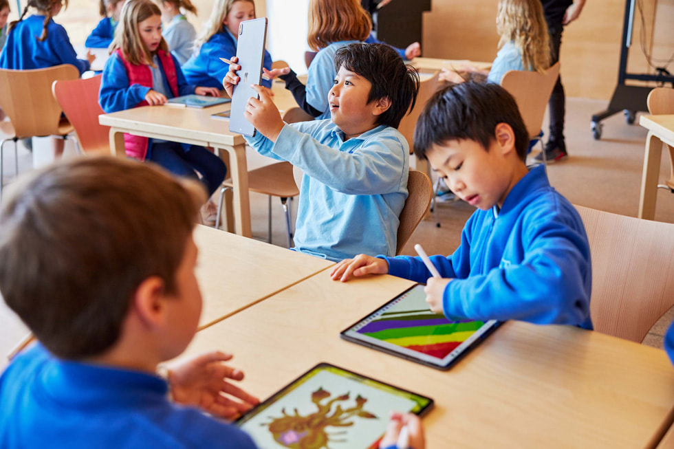 学生们在桌旁使用 iPad Pro 和 Apple Pencil。