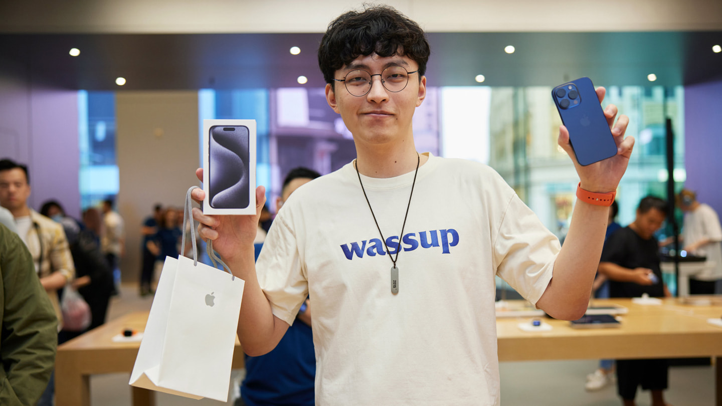 一位年轻顾客正在展示新购入的蓝色 iPhone 15 Pro Max。