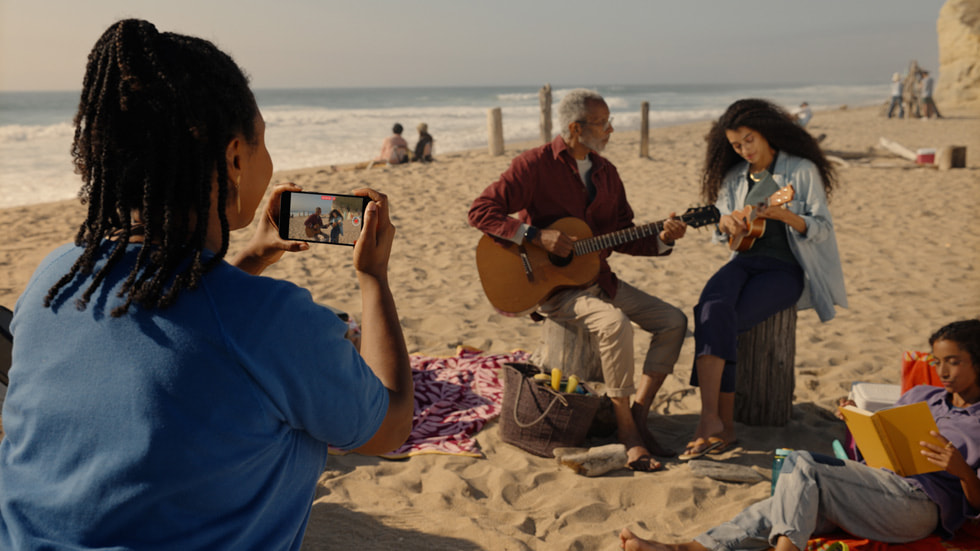 一个人在海滩上使用 iPhone 15 Pro 拍摄空间视频。