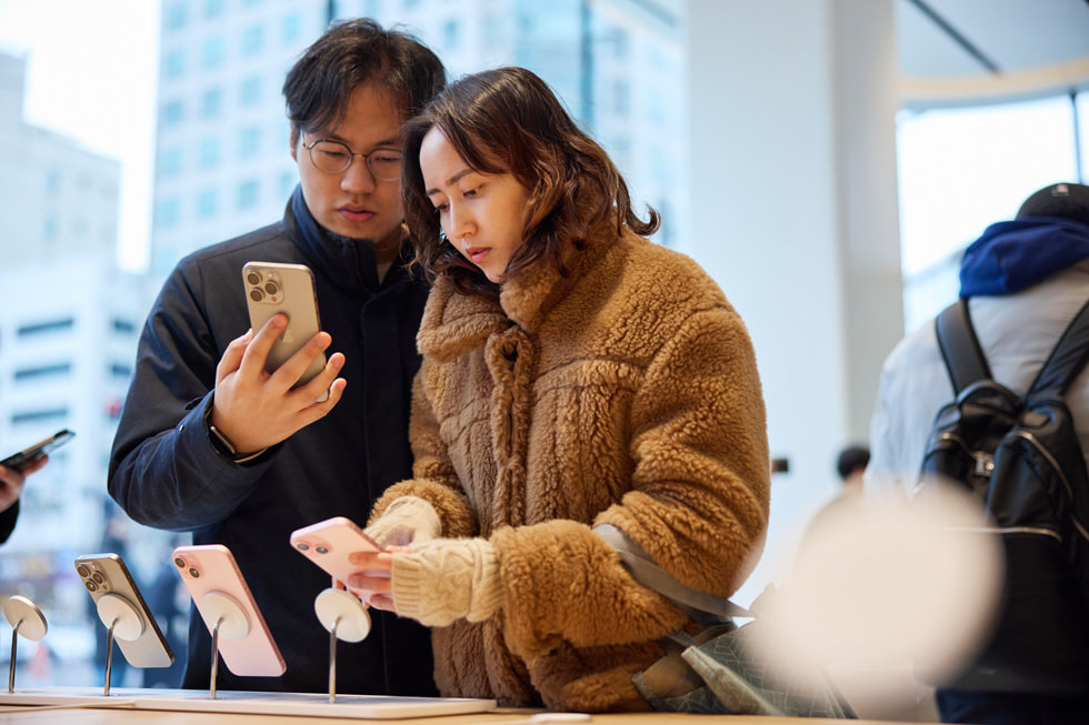 两位顾客正在查看 iPhone 15 系列机型。