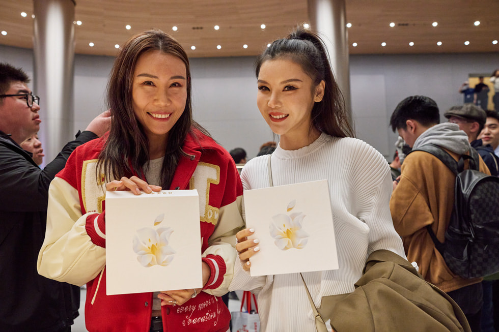 顾客们展示 Apple 静安零售店开幕时的纪念礼品。