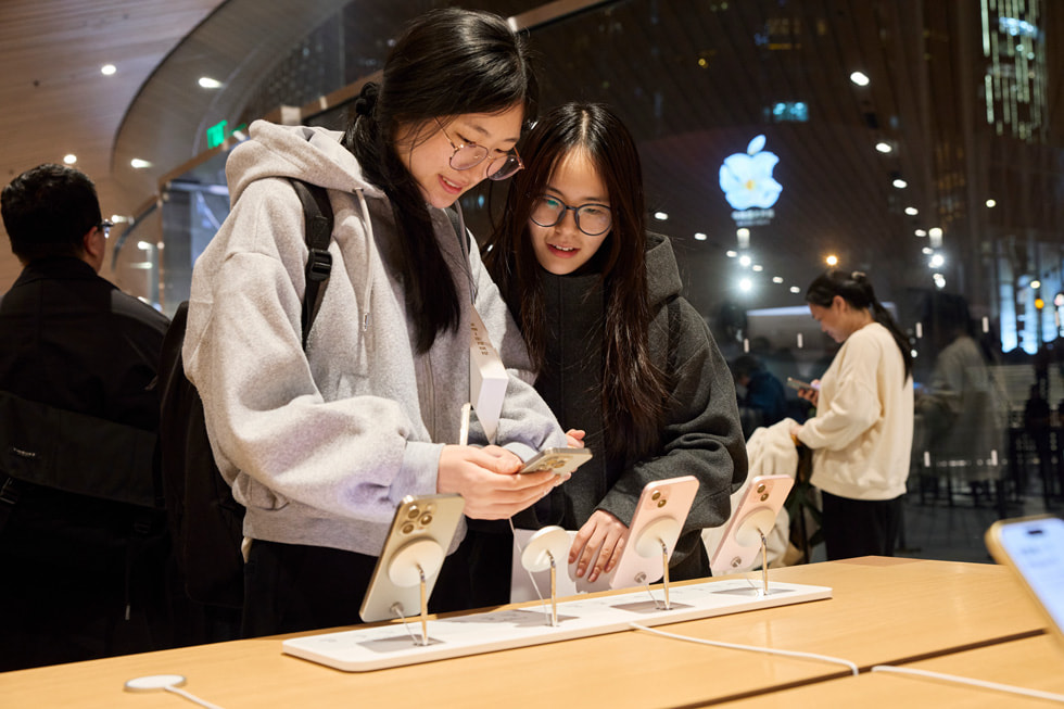 Apple 静安零售店的顾客站在 iPhone 15 系列产品的展示桌旁。