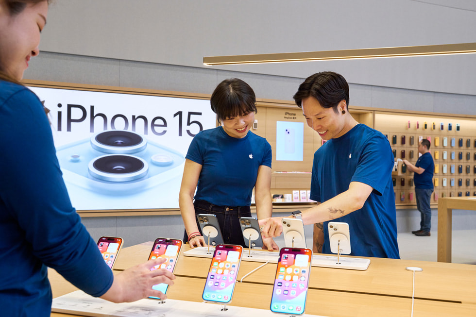 团队成员在店内查看产品展示桌上的 iPhone 15 设备。