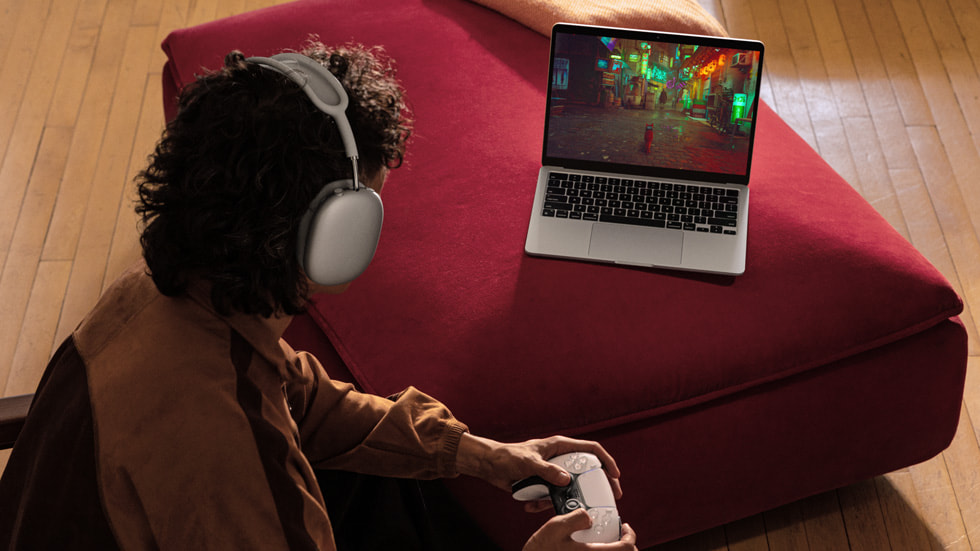 一个人头戴着耳机，在用新款 MacBook Air 玩游戏。