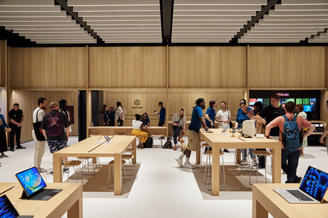 一家 Apple Store 零售店内部，顾客和员工正在交流互动。