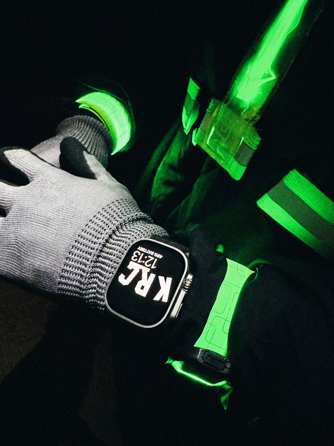 夜间拍摄的特写照片：一位跑者佩戴 Apple Watch Ultra 的手腕。
