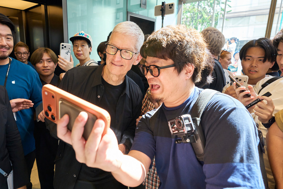 Apple 银座零售店内，一位顾客和 Tim Cook 自拍合影。