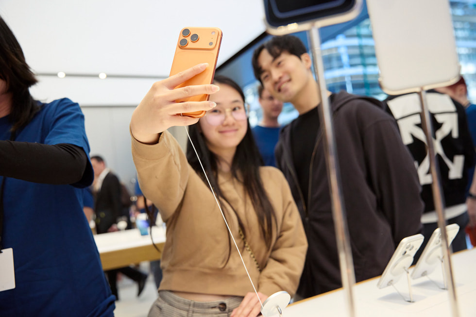 位于澳大利亚悉尼的 Apple 悉尼零售店内，两位开心的顾客使用 iPhone 17 Pro 拍摄自拍。