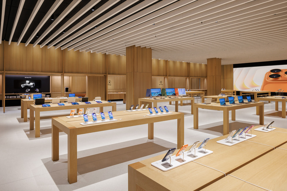 Apple 北京荟聚零售店内部照片，包括成行的轻木展示台，上面摆放着各种 Apple 产品。 