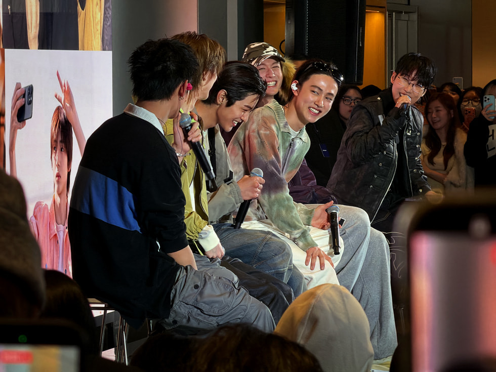 在首尔 Apple 明洞零售店，CORTIS 的团员们面带微笑，手持麦克风坐在一起。