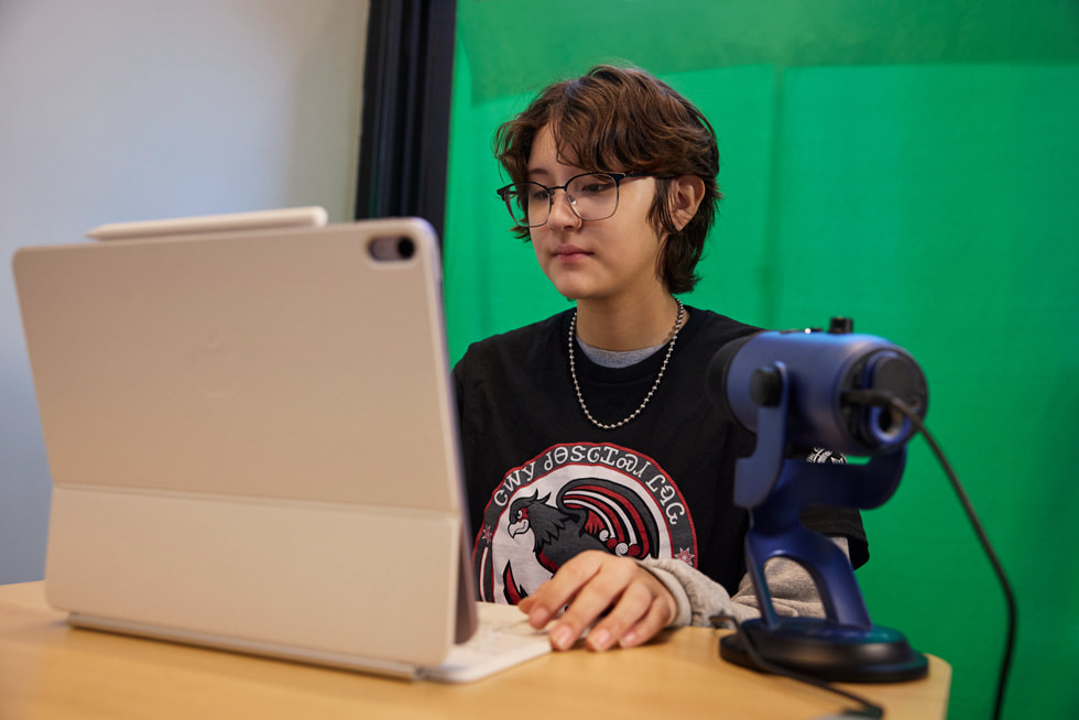 图中一名学生正在使用 iPad 学习，桌上还有一个麦克风。
