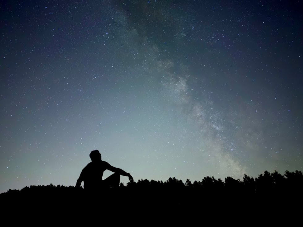 使用 iPhone 18 Pro 夜间模式拍摄的照片，展示星空下的人物剪影。