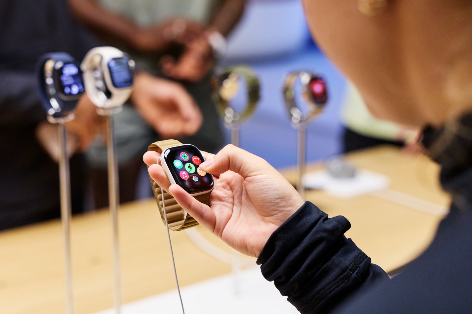 一位顾客在 Apple 考文特花园零售店内浏览 Apple Watch Series 12 的功能。