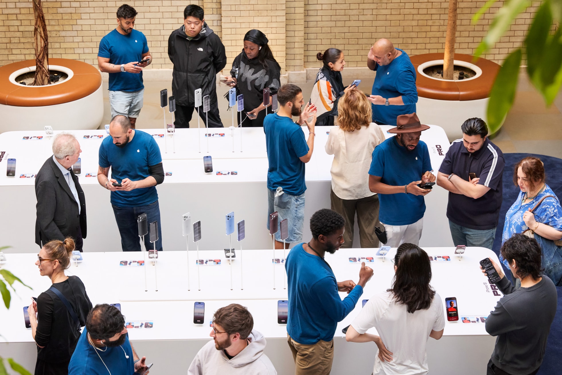 Apple 考文特花园零售店的团队成员在 iPhone 展示桌前为顾客提供协助。