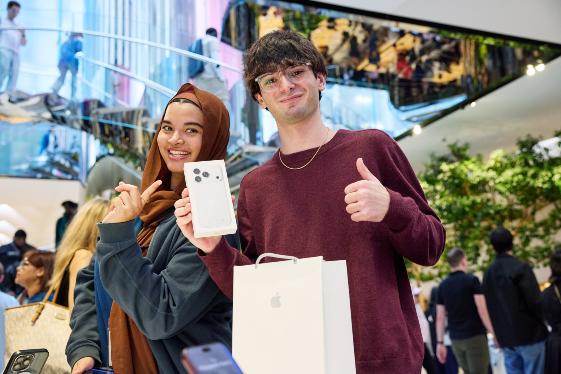 一位顾客手持 iPhone 18 Pro 购物袋，做出竖起大拇指的手势。
