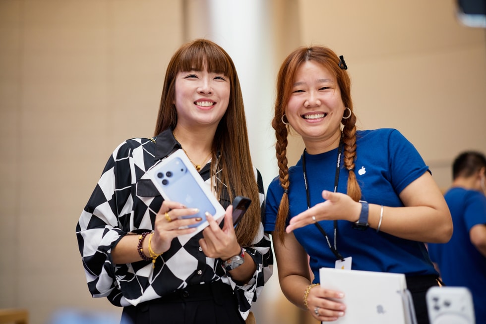 一位顾客在 Apple 静安零售店向面带微笑的团队成员展示刚刚购买的 iPhone 18 Pro。
