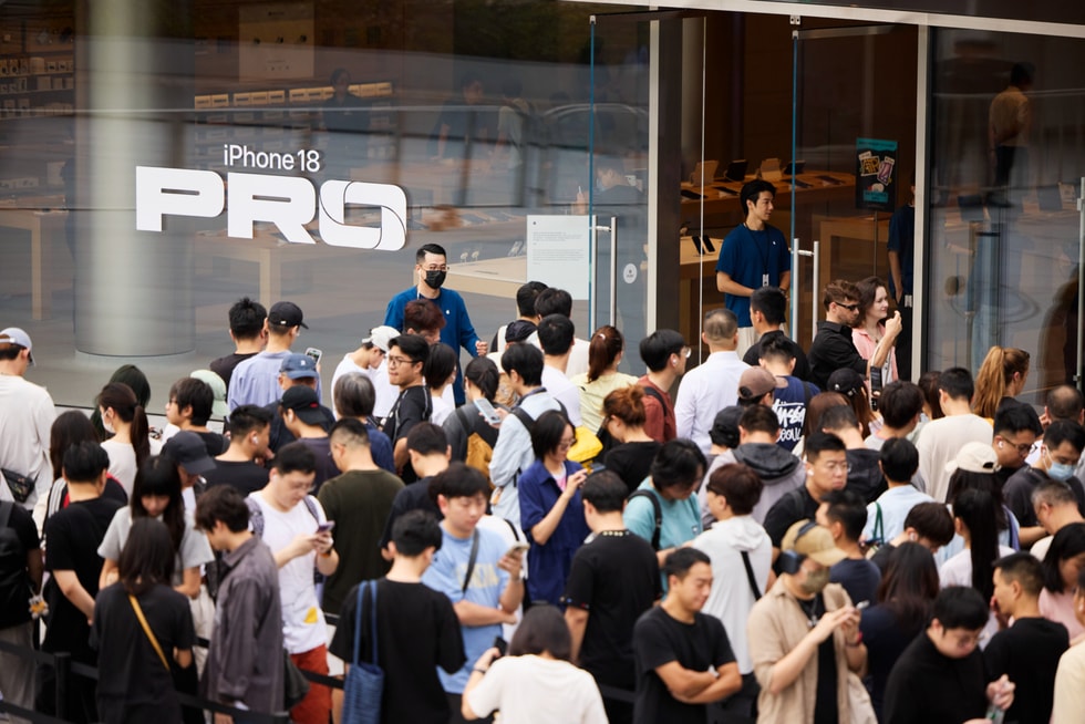 顾客站在 Apple 静安零售店外等待开门，团队成员在一旁观看。