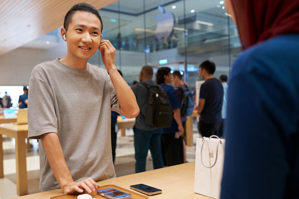 一位顾客在 Apple The Exchange TRX 零售店内试戴 AirPods 5。