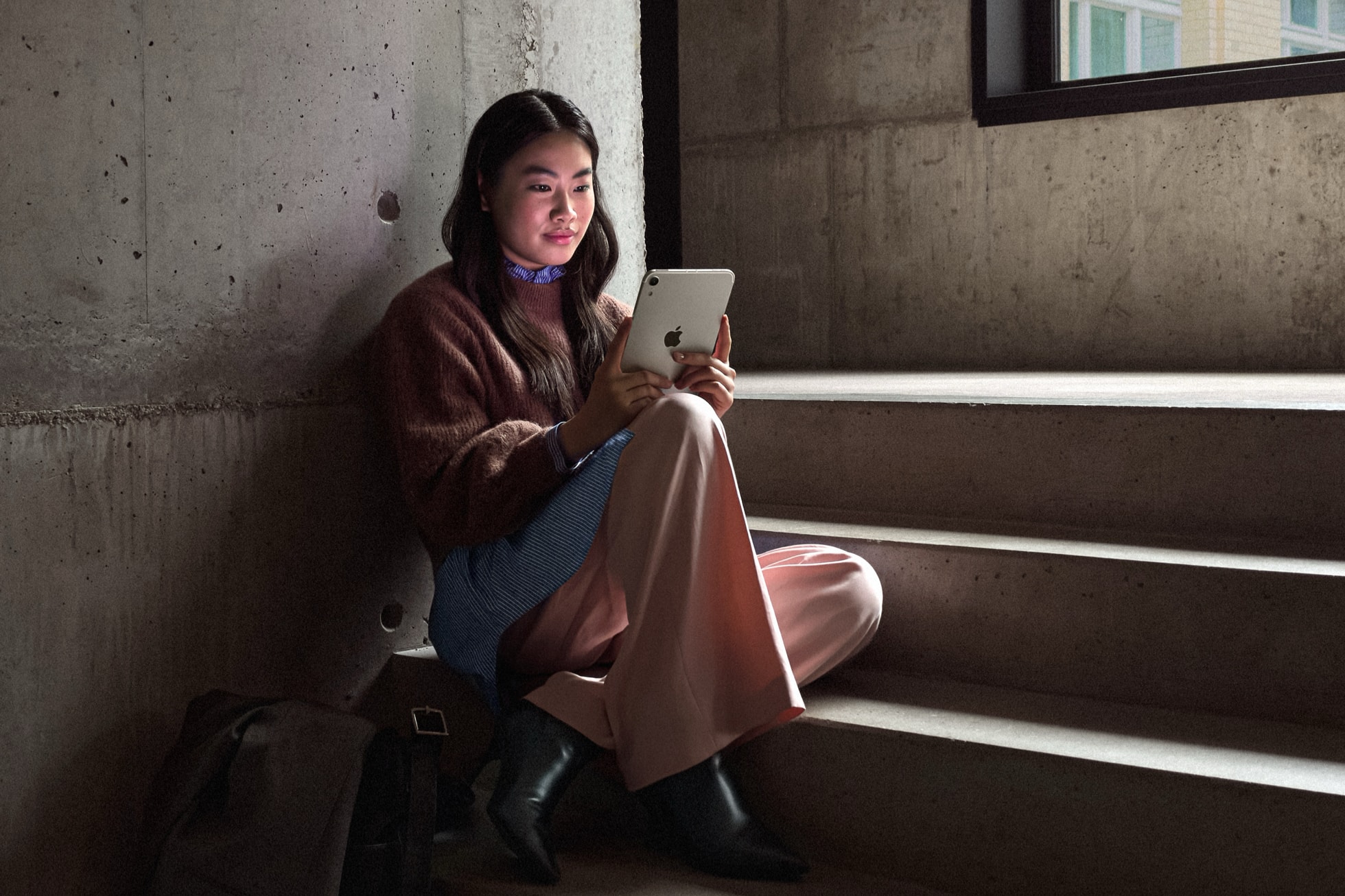 一个人手持 iPad mini 坐在台阶上。