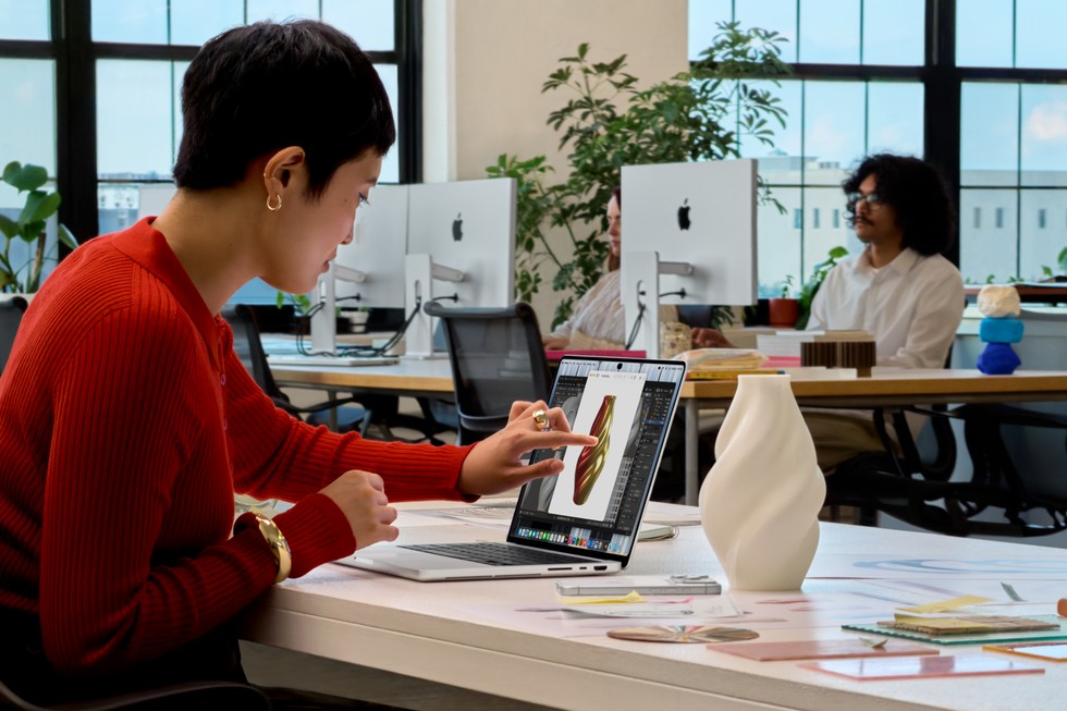 一名用户坐在办公室桌前，使用触控操作配备 PROLED XDR 显示屏的 MacBook Pro。