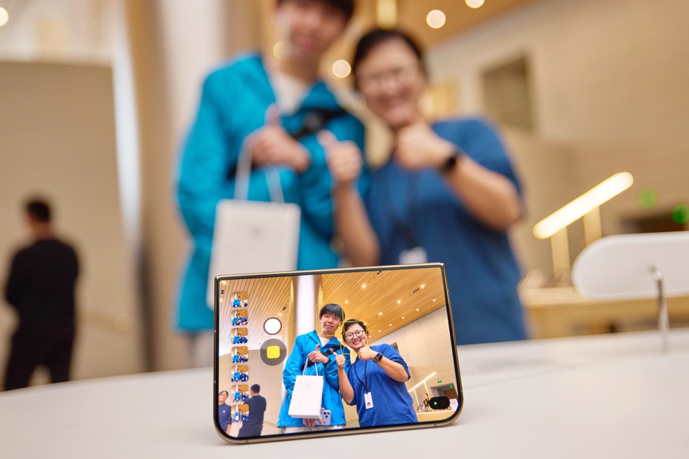 Apple 静安零售店内，一位顾客和一名 Apple 团队成员正在用 iPhone Duo 自拍。