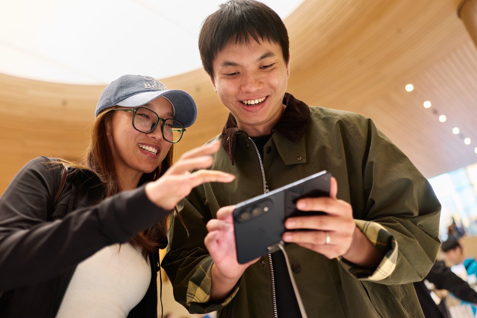 Apple 静安零售店外，两名顾客在夜空下试用 iPhone Duo。