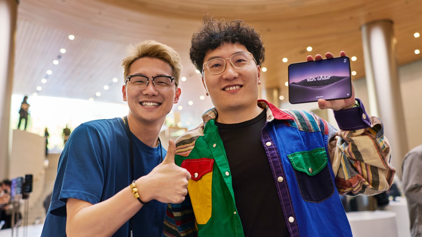 在 Apple 静安零售店，一位顾客举起 iPhone Duo，Apple 团队成员竖起拇指做出回应。