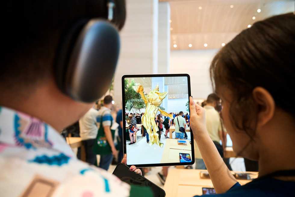 一名团队成员正在帮助顾客在 Apple Brompton Road 零售店内使用 iPad Pro 探索“United Visions” AR 体验。