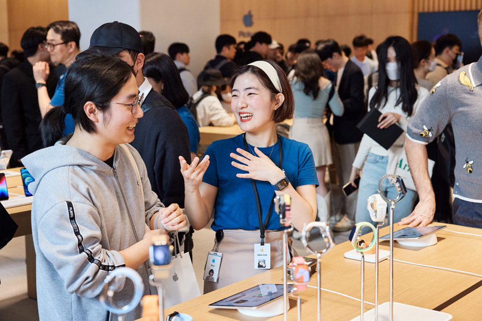 Apple Gangnam 零售店内，一名 Apple 团队成员正在与顾客讨论 Apple Watch。