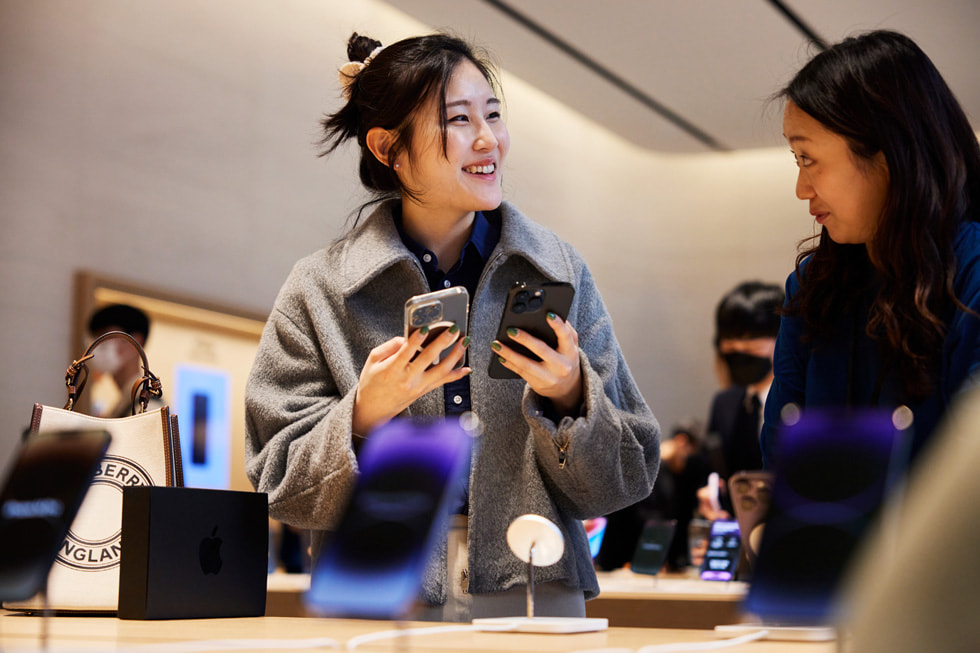 首尔 Apple Gangnam 零售店内，一位顾客举起新款 iPhone 14 Pro。