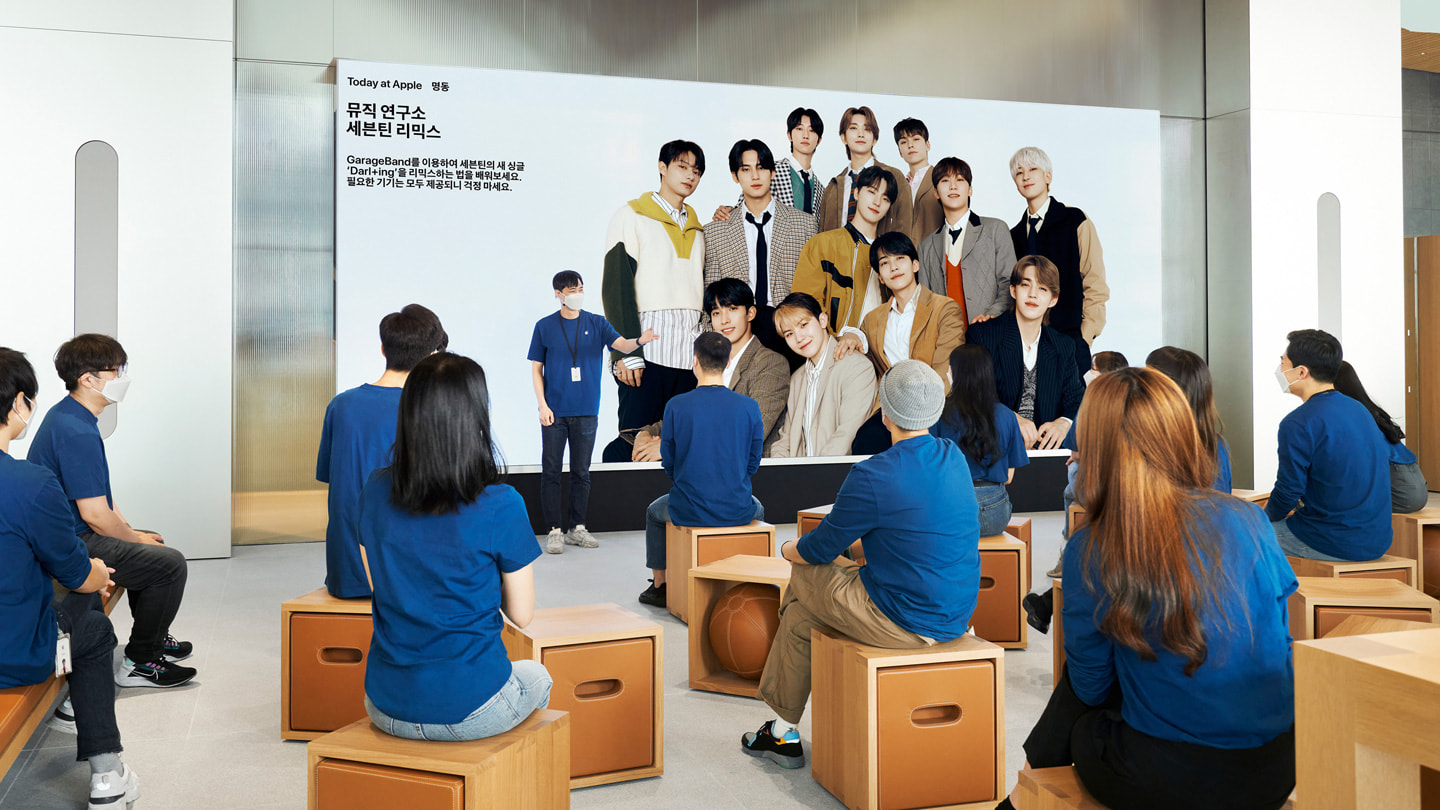 在 Apple 位于首尔的全新零售店—— Apple 明洞零售店内，顾客们坐在 Video Wall 影像墙前的 Forum 互动坊区域。