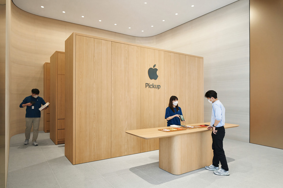 Apple Pickup 到店取货区内，一位顾客正与零售店员工交谈。