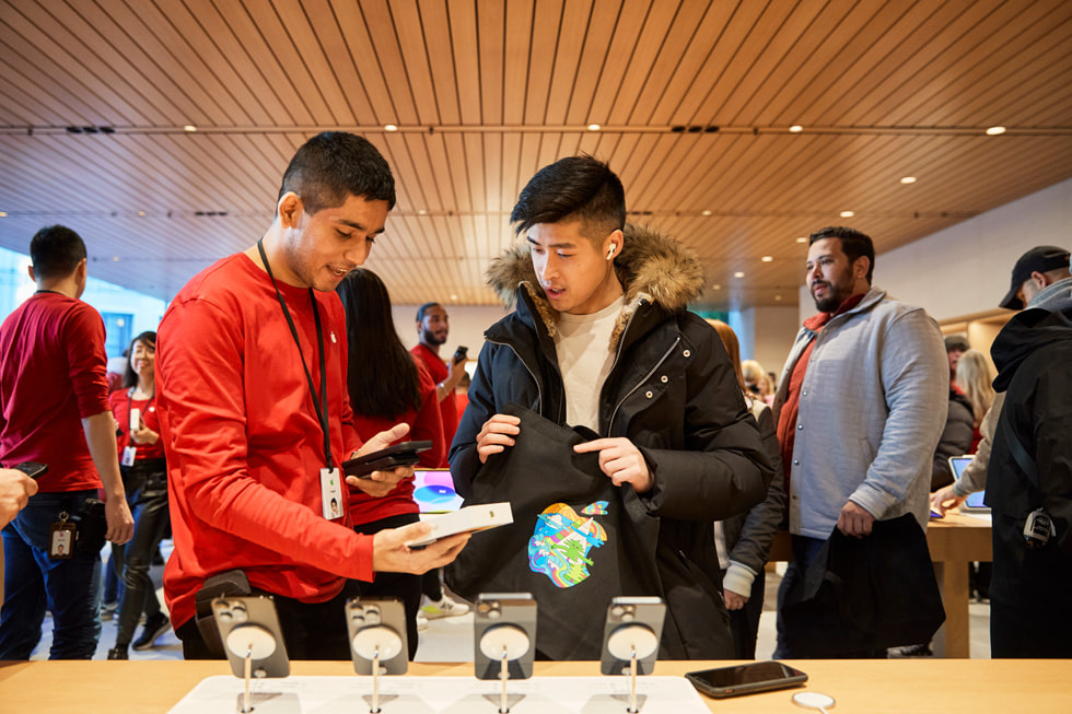 加拿大温哥华 Apple Pacific Centre 零售店内，团队成员协助顾客选购 iPhone 14 Pro。