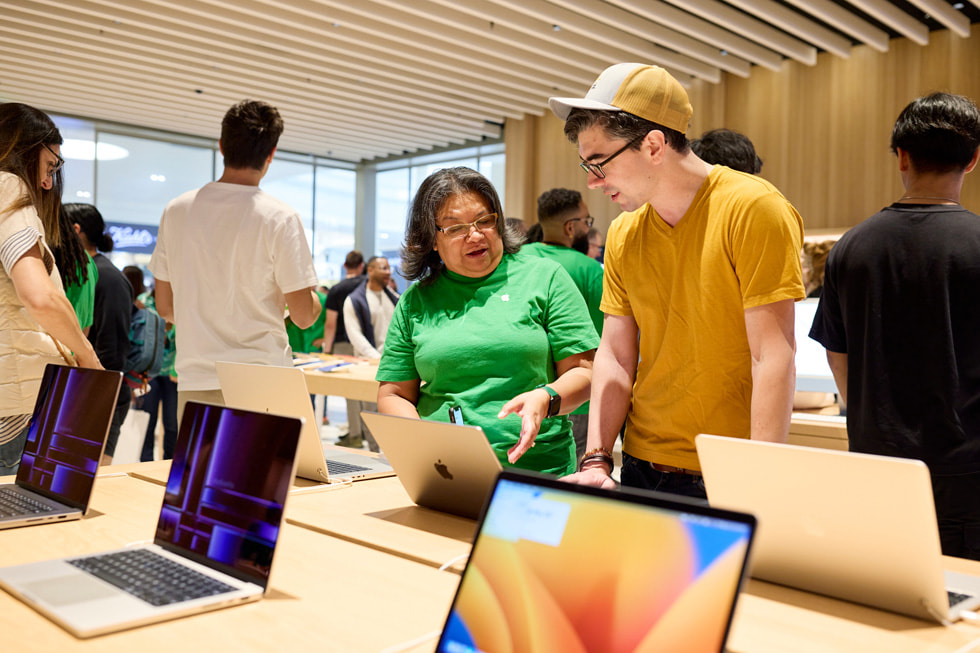 一名团队成员在向一位顾客展示最新 Mac 系列产品。