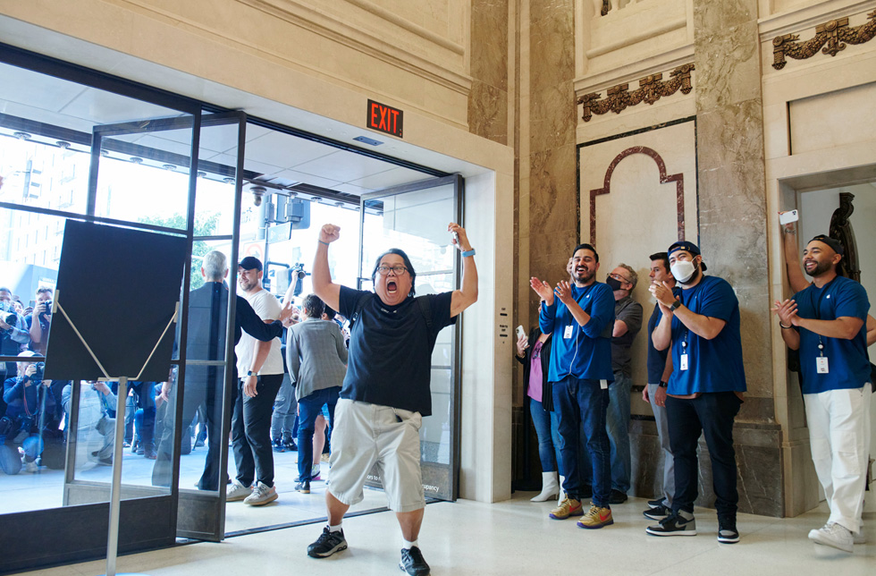 一位顾客在走进 Apple Tower Theatre 时，举起手臂以示庆祝。