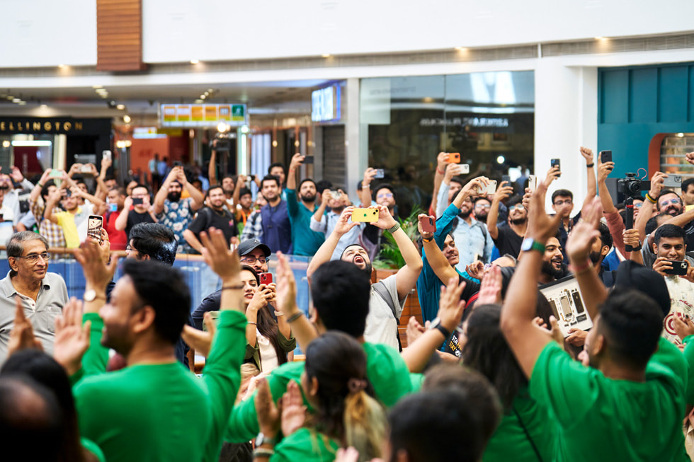 大批顾客在 Apple Saket 零售店外排队，其中许多人都在举起手拍照。