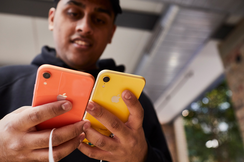 一名顾客正在比较珊瑚色和黄色版 iPhone XR。 